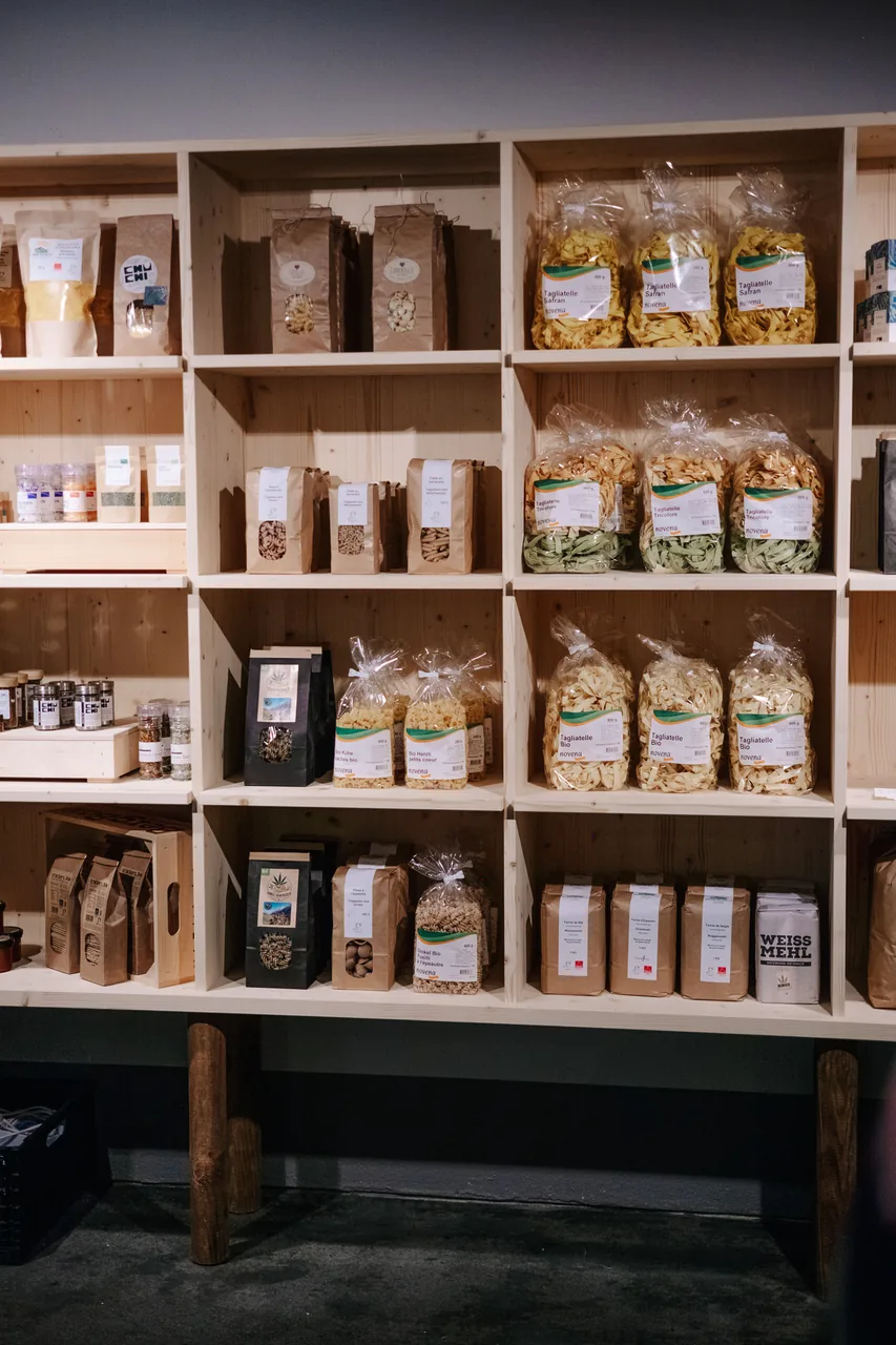 Étagère en bois avec des pâtes emballées et des produits secs au Hofladen Wallis